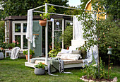 Cosy garden corner with sunbed, cushions and plants in summer