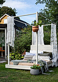 Lounge bed with lace curtains and cushions in the garden