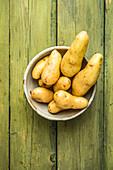 Raw potatoes in their skins on a wooden base