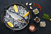 Raw sea bass on ice with spices and herbs