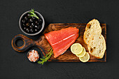 Raw salmon fillet with ciabatta and olives