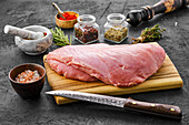 Raw turkey breast on wooden board with spices