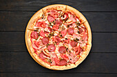 Pizza with salami, champignon mushrooms and tomato, top view