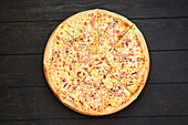 Pizza with parma ham, red onion and assortment of cheese, top view
