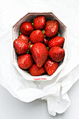 Strawberries in a white paper bowl