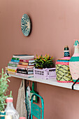 Decorative wall shelf with books, plants and colourful wicker bottles