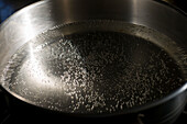 Wide stainless steel pot with water about to begin boiling