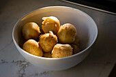 White bowl filled with small yellow Yukon potatoes in golden, late afternoon sunlight