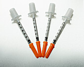Four medical syringes with orange caps