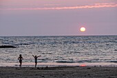 Frankreich, Charente Maritime, Insel Oleron, junge Frauen am Strand bei Sonnenuntergang