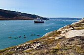 Greenland, west coast, Disko Bay, Quervain Bay, kayaks progressing among icebergs, Hurtigruten's MS Fram cruise ship in the background