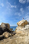 France, Finistere, Penmarch, hiker on the rocks of Saint-Guenolé