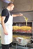 Frankreich, Hautes Pyrenees, Aure-Tal, Ancizan, Geschäft Kuchengeschichten, Herstellung eines Spießkuchens über dem Holzfeuer gekocht