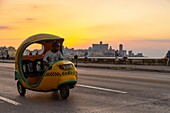 Cuba, Havana, district of Habana Vieja listed as World Heritage by UNESCO, coco-taxi on the Malecon with background Vedado