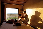 Morocco, Western Sahara, Dakhla, woman giving a massage to another woman at the spa of the kitesurf camp Dakhla Attitude, with the beach and the lagoon appearing through the window