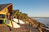 Morocco, Western Sahara, Dakhla, Moroccan surfers with their boards in front of the ocean in West Point Hotel