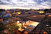 Marokko, Tanger Region Tetouan, Tanger, Dar Nour Hotel, Paar auf einer Bank auf der Terrasse des Gästehauses Dar Nour mit Blick auf die Kasbah bei Einbruch der Dunkelheit