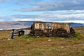 Greenland, West Coast, North Star Bay, Wolstenholme fjord, Dundas (Thule), Inuit Igloo, traditional house with peat walls and, from the beginning of the 20th century, an internal wooden structure, the ice cap in the background