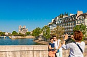 France, Paris, area listed as World heritage by UNESCO, Ile de la Cite, tourist photographing in front of Notre Dame cathedral