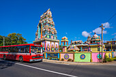 View of red bus and Sri Draubadi Ammen Hindu Temple on sunny day, Mauritius, Indian Ocean, Africa