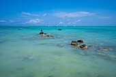 Blick auf einen Mann beim Fischen am Mont Choisy Beach und den türkisfarbenen Indischen Ozean an einem sonnigen Tag, Mauritius, Indischer Ozean, Afrika