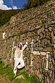 Woman dressed in llama onesie at the llama wall at Choquequirao, Peru, South America