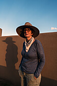 Usa, New Mexico, Santa Fe, Porträt einer Frau mit Strohhut an einer Lehmmauer in der High Desert