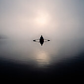 Mann rudert Boot im Morgennebel, Lake Placid, NY, USA