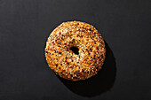 Overhead view of bagel with seeds on black background