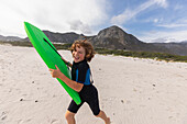 South Africa, Hermanus, Smiling boy running on beach with body board