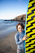 Mexiko, Baja, Pescadero, Porträt eines Jungen mit Surfbrett am Strand