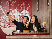 Chinesisches Paar posiert für Handy-Selfie im Restaurant