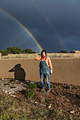 USA, New Mexico, Santa Fe, Porträt einer Frau im Garten mit Doppelregenbogen im Hintergrund