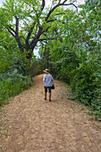 Rear view of woman walking on footpath in High Desert oasis