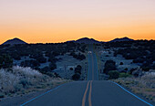 USA, New Mexico, Galisteo, Auto auf Wüstenstraße in der Abenddämmerung