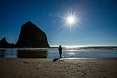 USA, Oregon, Silhouette einer Frau, die in der Nähe des Haystack Rock in Cannon Beach steht