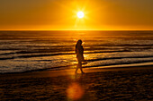 Silhouette einer Frau, die am Cannon Beach spazieren geht