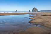 USA, Oregon, Sand, shallow pools of water and rock formations at Cannon Beach 