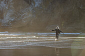 USA, Oregon, Newport, Frau steht mit ausgestreckten Armen am Sandstrand