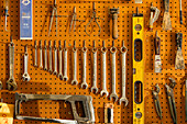 Tools on pegboard hooks on wall of wood and metal shop