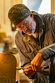 Ein erfahrener Holz- und Metallhandwerker arbeitet mit Elektrowerkzeugen in der Werkstatt