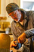 Älterer Holz- und Metallhandwerker arbeitet mit Werkzeugen in der Werkstatt