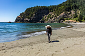 USA, Oregon, Brookings, Senior woman walking on beach on sunny day