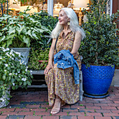 Ältere blonde Frau sitzt auf einer Bank im Einkaufsviertel