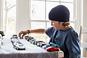 Junge (10-11) spielt zu Hause mit Spielzeugautos