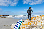 Boy (10-11) with body board standing on Voelklip Beach