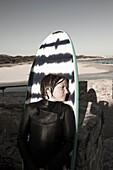 Portrait of boy (10-11) posing against surfboard at Onrus Beach