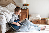 Jugendliches Mädchen (16-17) spielt Gitarre im Schlafzimmer