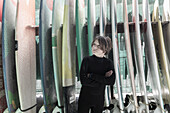 Boy (10-11) posing in front of surfboards