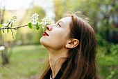 Schöne Frau riecht an einer Blume im Obstgarten
